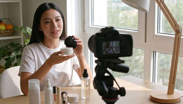 Asian beauty creator recording skincare tutorial with dslr in natural light home studio