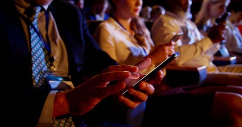 Business professionals using mobile phones at conference