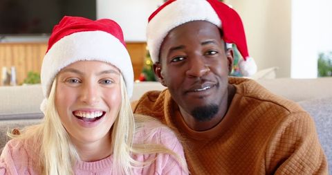 Diverse couple embracing holiday spirit at home in santa hats