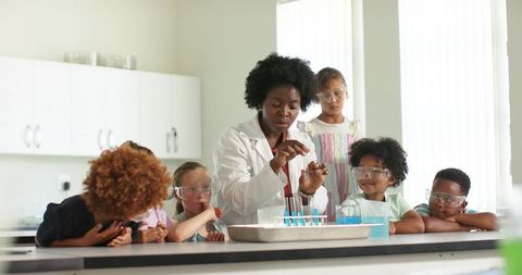 African american teacher leading hands-on pipette experiment with diverse children in classroom lab