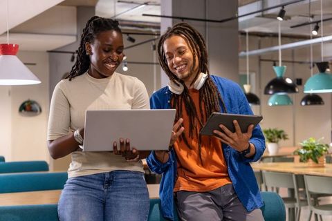 African American coworkers collaborating with laptop and tablet in bright coworking space