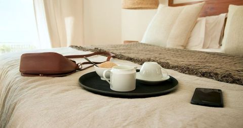 Cozy Bed with Coffee Tray and Personal Items in Neutral Setting