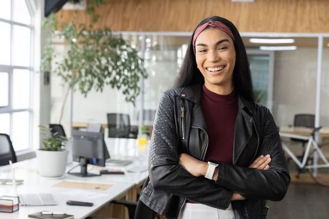 Confident young professional smiling with arms crossed in modern coworking office