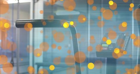 Displaying treadmill handrail and control console with stop button and warm bokeh lights