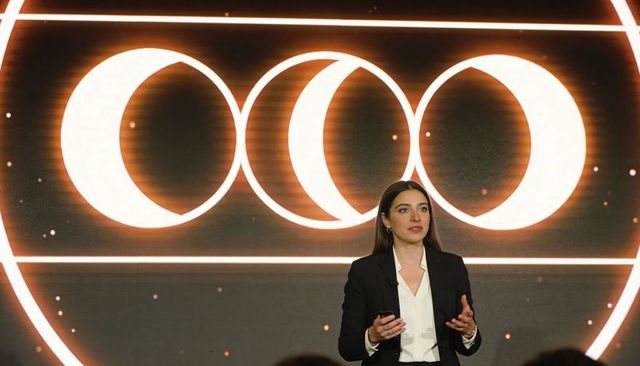 Woman delivering keynote presentation with crescent led graphics on conference stage