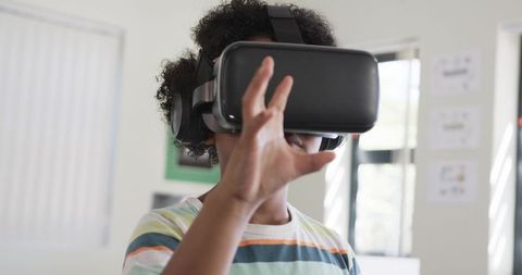 Student Wearing VR Headset Reaching and Exploring Virtual Reality Learning in Classroom