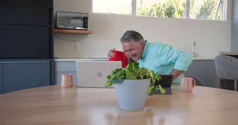 Elderly Couple Celebrating Online Success at Home with Gadgets