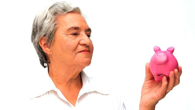 An elderly woman with grey hair is smiling while holding a pink piggy bank, symbolizing financial planning and retirement savings. This video is perfect for illustrating financial security, retirement concepts, savings strategies, and banking services aimed at seniors. Suitable for use in articles, promotional materials, or educational resources focusing on financial literacy and budgeting for senior citizens.