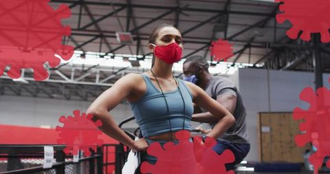 Wearing red mask and standing hands-on-hips after cardio workout in warehouse gym