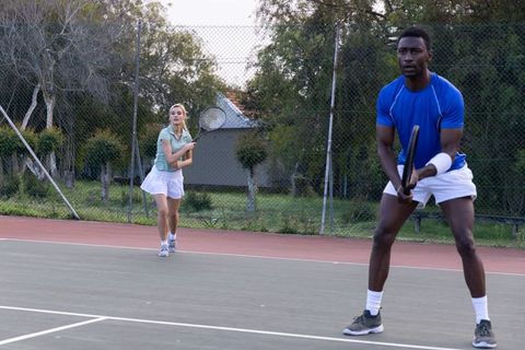 Doubles partners playing tennis on outdoor hard court showcasing teamwork and focus