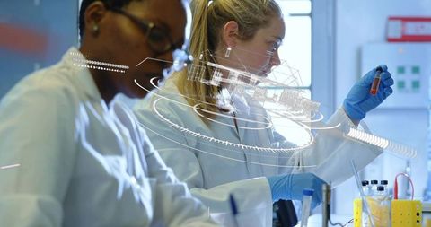 Researchers inspecting red test tube with augmented data overlay in modern biotech lab