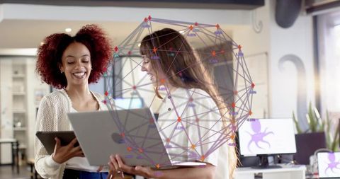 Colleagues collaborating with laptop, tablet in office showing network wireframe overlay