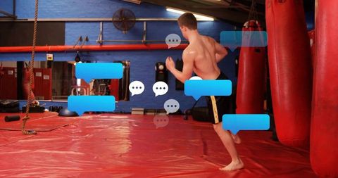 Shirtless Martial Artist Training in Dojo with Punching Bags