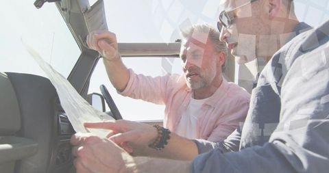 Planning road trip route, mature men examining paper map inside car, navigation discussion