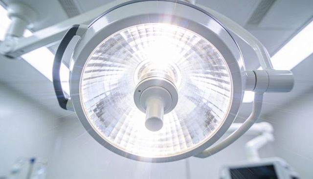 Overhead surgical light illuminating operating room with faceted reflector and radial beam