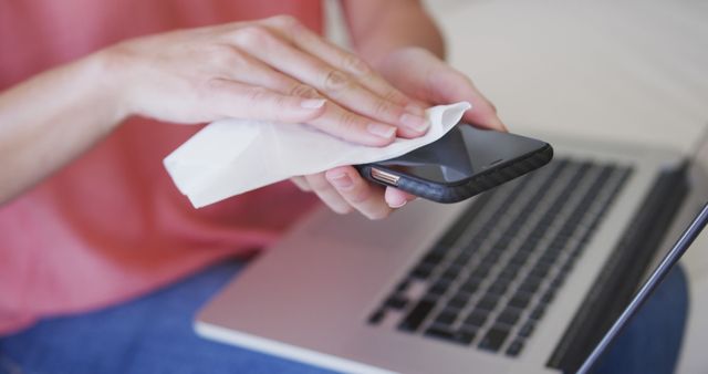 Cleaning Smartphone with Disinfectant Wipe near Laptop in Office - Download Free Stock Images Pikwizard.com