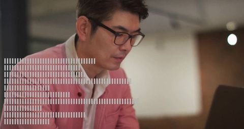 Professional man in pink blazer working at laptop in modern office