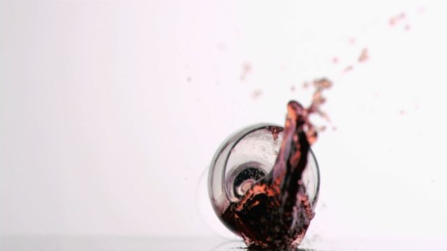 Red wine glass tumbling and creating a dynamic splash against a white background. Useful for concepts of accidents, mess, spilling drinks, and high-speed photography. Ideal for advertisements, blogs, articles, and educational materials focusing on beverage care, celebrating moments, and disaster preparations.