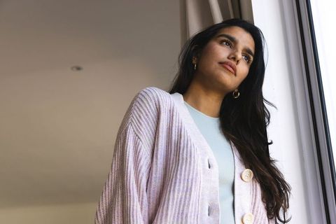 Serene indian woman gazing thoughtfully from window