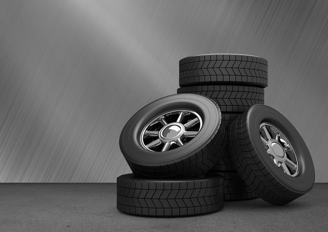 Car tyres stacked in front of grey background can be used in automotive repair, car maintenance promotions, transportation, and mechanical industry related content.