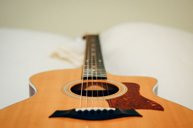 Close-up view of a wooden acoustic guitar, showing detailed craftsmanship and focusing on body and strings. Ideal for use in articles about music, musical instruments, guitar lessons, or craftsmanship. Could also be used in promotional materials for folksy events or music school advertisements.