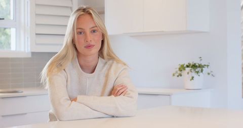 Serene young woman relaxing in minimalist white kitchen interior