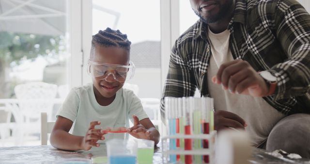 African american father and son sitting at table doing chemistry experiments at home. Family, fatherhood, togetherness, science and domestic life, unaltered.