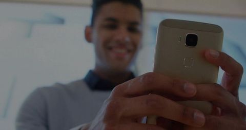 Young Man Engaging with Smartphone Indoors