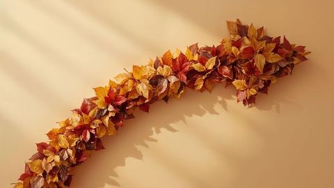 Curved arrow autumn leaves garland against warm beige background