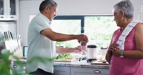 Senior Couple Preparing Healthy Drink in Bright Kitchen