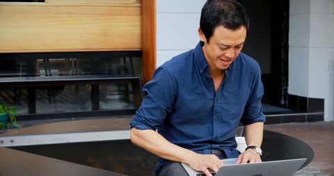 Focused man working on laptop outdoors