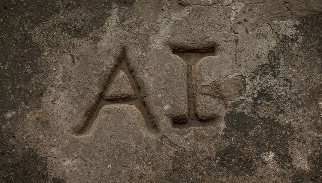 Weathered stone carving revealing letters a and t on textured monument slab with lichen