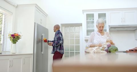 Senior couple unpacking groceries in modern kitchen