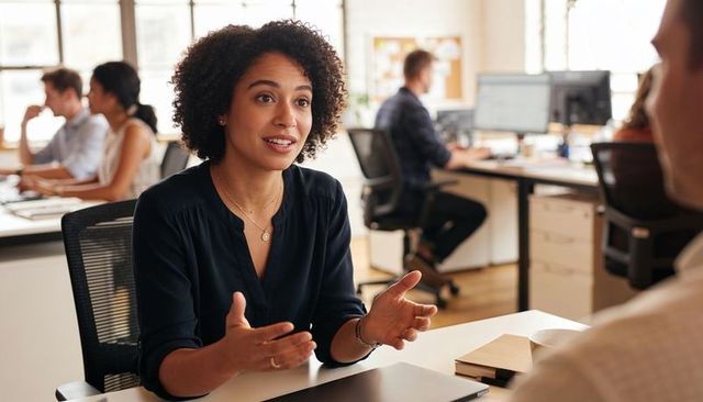 Professional woman leading one-on-one discussion in modern open-plan office, collaborating