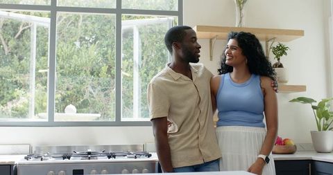 Couple smiling and planning dinner while cooking in bright modern home kitchen