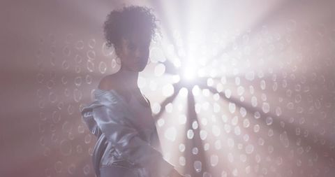 Backlit african american woman posing in haze with off-shoulder jacket, starburst bokeh