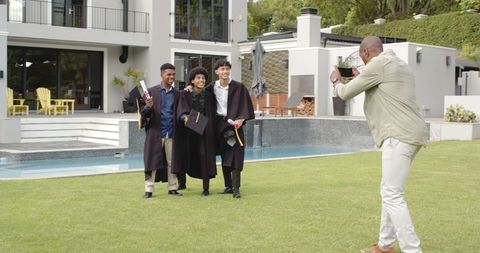 Proud Parent Photographing Diverse Graduates Celebrating with Diplomas