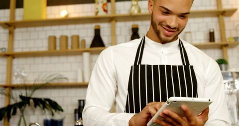 Cafe Attendant Using Tablet in Cozy Artisan Coffee Shop Environment