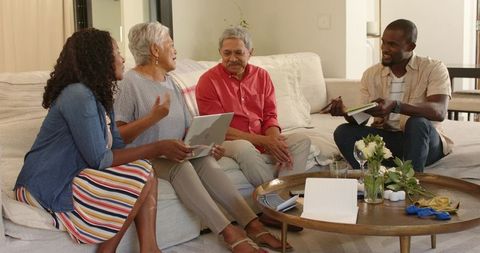 Multigenerational family having meeting on sofa using tablet and notebook