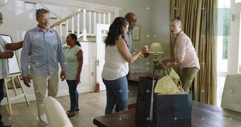 Adults gathering in home dining room pouring wine and exchanging gifts during casual celebration