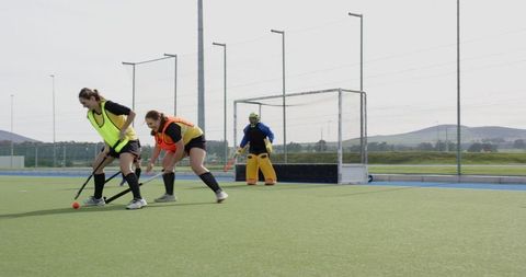 Diverse female field hockey team competing on pitch