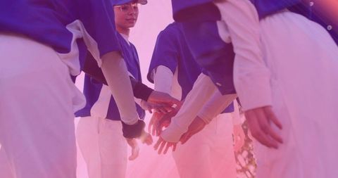Young Female Baseball Players Huddling in Unity at Sunset