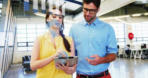 Young professionals collaborating with tablet in open-plan office for digital brainstorming