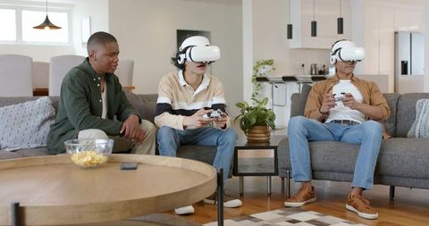 Diverse male friends playing VR games with white headsets in modern living room
