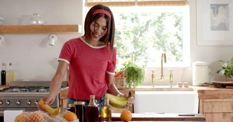Woman Organizing Fruits on Wooden Kitchen Counter in Bright Setting