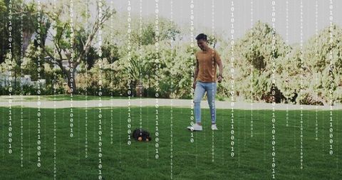 Asian man playing with dog on backyard lawn with binary code overlay blending tech and leisure