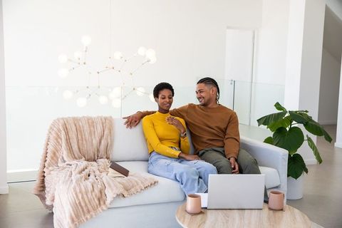 Diverse Couple Relaxing in Minimalist Living Room with Technology
