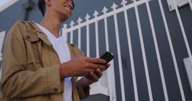 Young Man Smiling and Using Smartphone in Urban Setting - Download Free Stock Images Pikwizard.com