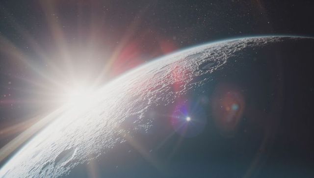 Cratered lunar surface with radiant sunrise and lens flares