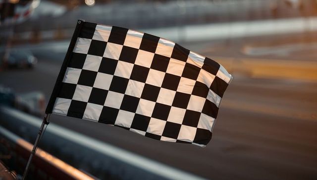 Fluttering checkered flag at racetrack finish line during golden hour victory moment